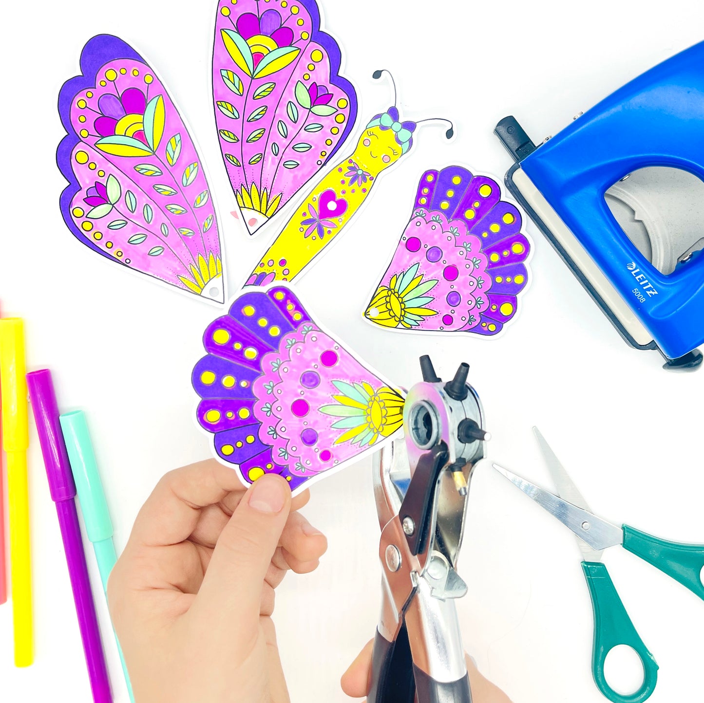 using a hole punch to make hold for movable wings on a butterfly craft