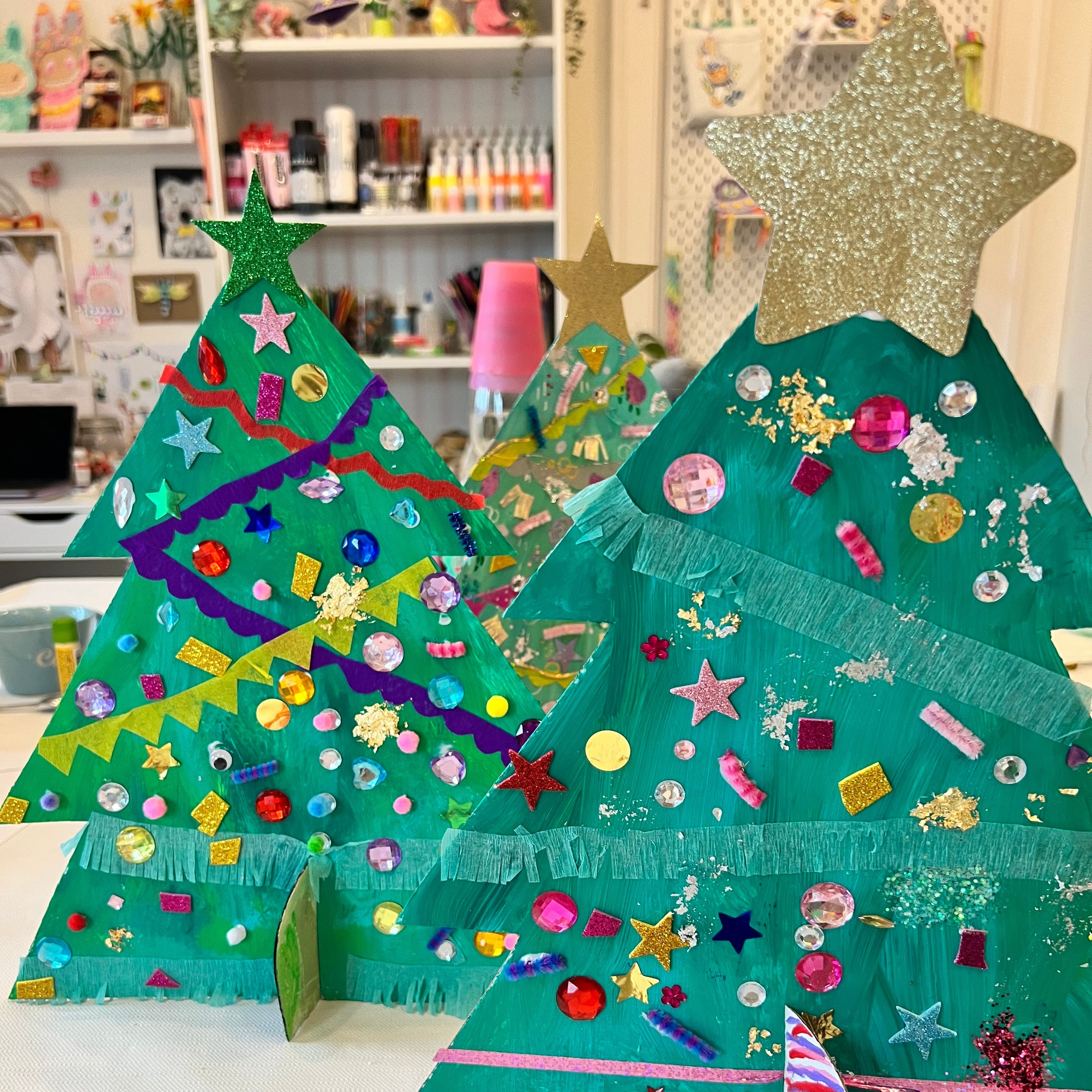 Decorative Christmas trees made from green paper with colorful decorations on a white surface.
